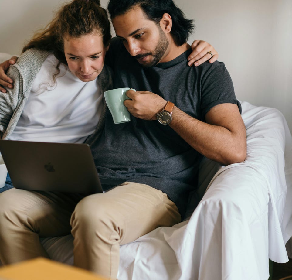 Multiethnic couple surfing net on laptop in new house